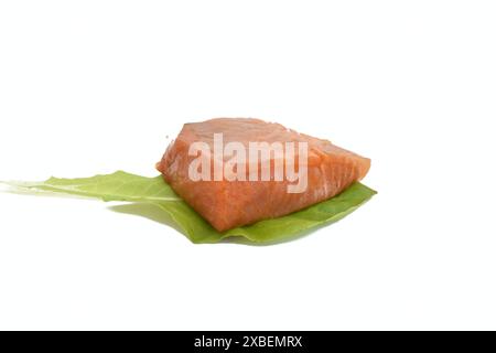 Ein Stück Lachsfisch liegt auf grünen Blättern. Der Fisch ist bereit zu essen. Stockfoto