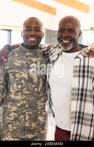 Junger afroamerikanischer Soldat in Uniform steht zu seinem Reifen, lächelnden Vater Stockfoto