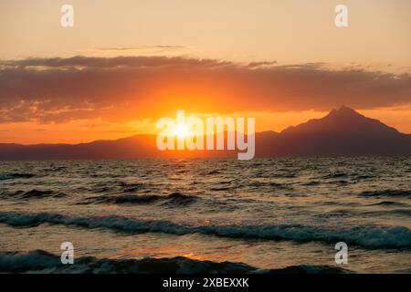 Sonnenaufgang von Sarti, Griechenland, mit dem beliebten Mönchsberg Arthos. Das Foto wurde vom Strand Sarti gemacht. Das Sonnenlicht lässt die Wellen schön leuchten. Stockfoto