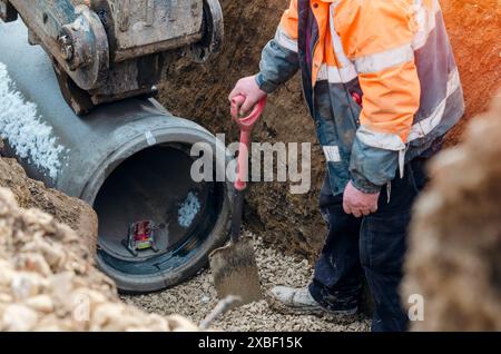 Erdarbeiter verlegen neue Betonrohre bei Tiefentwässerungsarbeiten am neuen Wohnprojekt Stockfoto