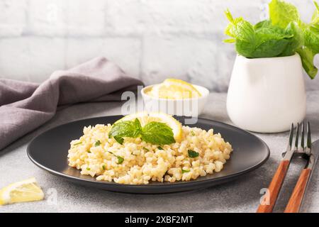 Gekochter Bulgur mit frischer Zitrone und Minze auf einem Teller. Ein traditionelles orientalisches Gericht namens Tabouleh Gray Betonhintergrund Stockfoto