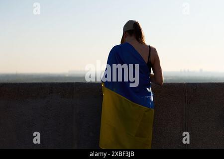 Ukrainisches Mädchen mit Nationalflagge bedeckt. Traurige junge Patriotin der Ukraine senkte ihren Kopf in Gedanken. Kiew - 1. Juni 2024 Stockfoto