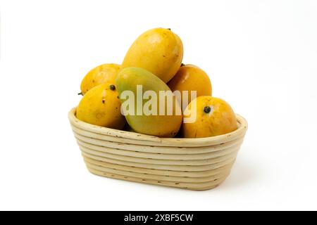 Stapel reifer Mango auf einem Korb aus Rattan, isoliert auf weißem Hintergrund, Draufsicht Stockfoto