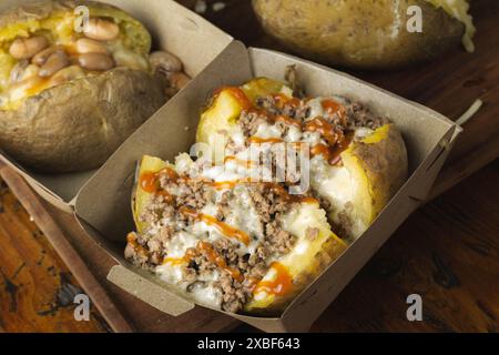 Hausgemachte beladene gebackene Kartoffeln mit Cheddar, Hackfleisch und süß-saurer Sauce Stockfoto