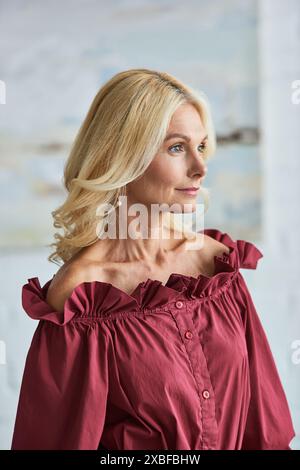 Eine reife Frau mit blonden Haaren in einer stilvollen roten Bluse. Stockfoto