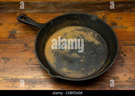 Rostige Eisenpfanne auf Holzbrett, Nahaufnahme Stockfoto