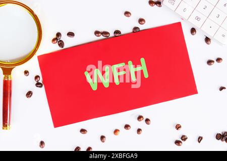 Konzeptbild mit Wort WFH. ARBEIT VON ZU HAUSE WFH auf einer roten Karte auf weißem Hintergrund in einer Komposition mit Kaffeebohnen und einer Lupe geschrieben Stockfoto