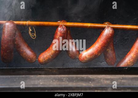 Würstchen hängen auf einem Regal in einem Offsetraucher mit dickem Rauch, geschlossen Stockfoto