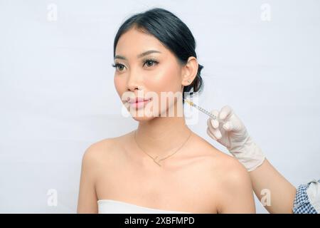 Raffinierte asiatische Frau, die sich Botox-Injektionen unterzieht, um Falten zu glätten Stockfoto