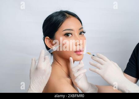 Junge asiatische Frau mit Haaren in einem Brötchen, die sich einer Fettentfernung unterzieht Stockfoto