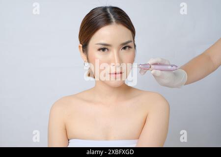 Schöne asiatische Frau, die sich einer Mikroneedling-Behandlung mit Dermapen unterzieht Stockfoto