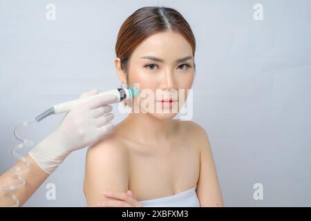 Charmante asiatische Frau, die SilkPeel-Gesicht für Hautverbesserung erhält Stockfoto