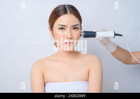 Junge asiatische Frau, die HF Ultraschall Oxygeneo Skin Enhancement Behandlung erhält Stockfoto