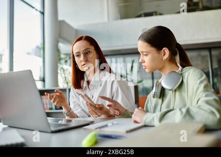 Eine rothaarige Frau unterrichtet ein Teenager-Mädchen und unterrichtet nach dem Unterricht gemeinsam mit einem Laptop. Stockfoto