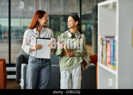 Eine rothaarige Frau unterrichtet ein Teenager-Mädchen in einer Bibliothek, beide vertieft in After-School-Unterricht Stockfoto