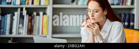 Eine rothaarige Tutorin unterrichtet fleißig online mit einem Laptop während eines Unterrichts nach der Schule. Stockfoto