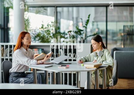 Eine rothaarige Frau unterrichtet ein Mädchen im Teenageralter in einem Büro, beide haben After-School-Unterricht mit einem Laptop für moderne Bildung. Stockfoto