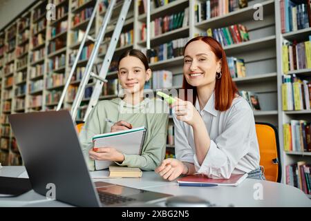 Ein Tutor und ein Teenager-Mädchen, eingetaucht in moderne Bildung, mit einem Laptop in einer gemütlichen Bibliothek. Stockfoto