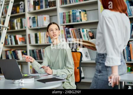 Eine rothaarige Tutorin unterrichtet ein Teenager in einer Bibliothek, während sie mit einem Laptop an After-School-Unterricht teilnehmen. Stockfoto