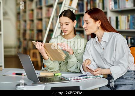 Ein rothaariger Tutor unterrichtet ein Teenager-Mädchen in einer Bibliothek, beide vertieft in einem Laptop für After-School-Unterricht. Stockfoto