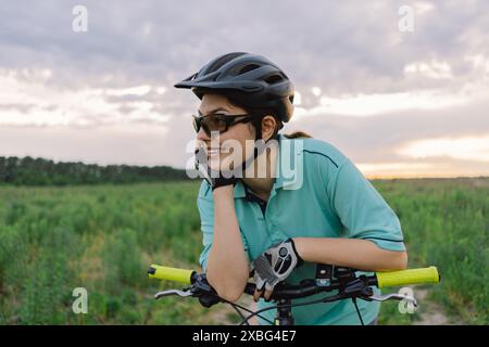 Frau mit Helm und Sonnenbrille fährt Fahrrad im Freien Stockfoto