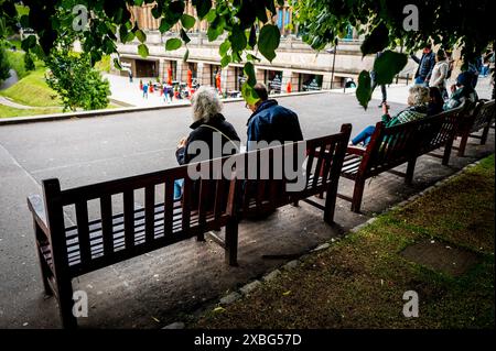 Leute sitzen auf einer Bank in den Princes Street Gardens in Edinburgh, Schottland Stockfoto