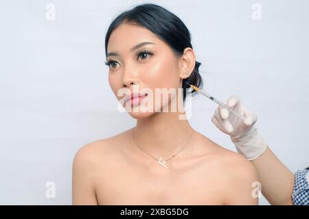 Schöne asiatische Frau mit Hochachtung, die Botox für jünger aussehende Haut bekommt Stockfoto