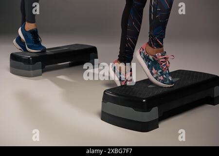 Ein junges, multikulturelles und passendes Paar in aktiver Kleidung, das in einem Studio tatkräftig auf einem Paar Steppern steht. Stockfoto