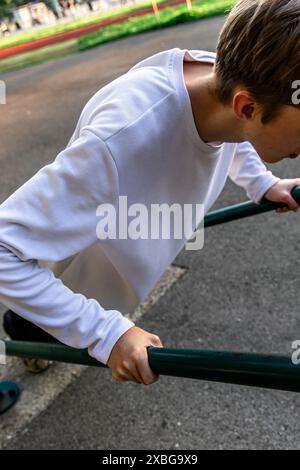 Junger Mann, der in einem Park Dips an parallelen Bars spielt Stockfoto
