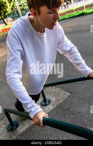 Junger Mann, der Tauchübungen an parallelen Bars im Outdoor Park durchführt Stockfoto