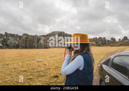 Eine Frau mit gelbem Hut fotografiert eine felsige Landschaft. Huayllay Stone Forest, Peru. Stockfoto