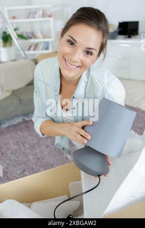 Frau, die eine Lampe aus einem Karton auspackt Stockfoto