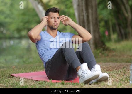 Mann, der morgens Sit-UPS im Wald macht Stockfoto