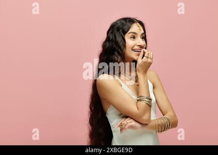 Junge indianerin mit langen Haaren, die vor einem rosa Hintergrund posiert. Stockfoto