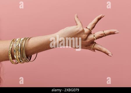 indische Frau, die goldene Armreifen an der Hand in einer stilvollen Pose zeigt. Stockfoto