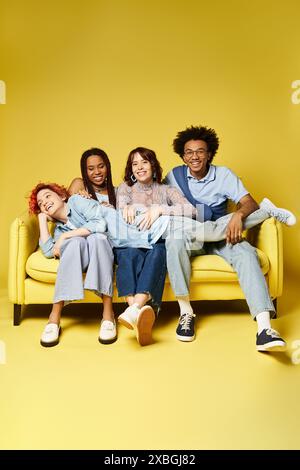 Eine vielfältige Gruppe junger Freunde in stilvollen Outfits, die sich auf einer leuchtend gelben Couch in Studioatmosphäre lässig entspannen und unterhalten. Stockfoto