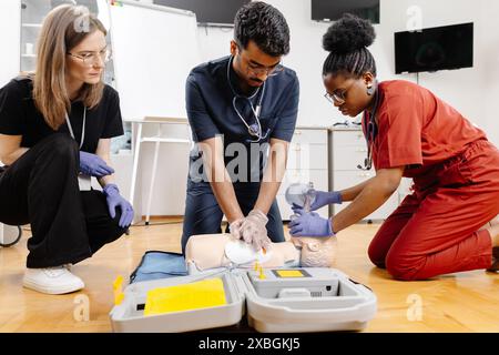 Drei Personen üben HLW-Techniken an einer Schulungspuppe im Klassenzimmer. Stockfoto