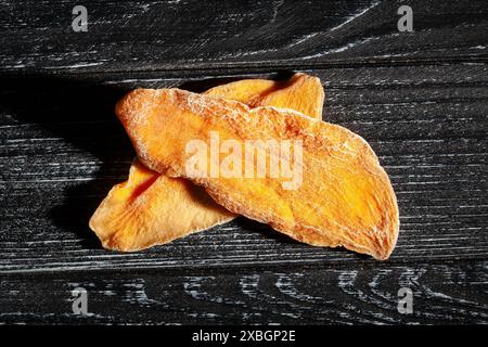 Trockene Mango auf schwarzem Holzhintergrund von oben Stockfoto