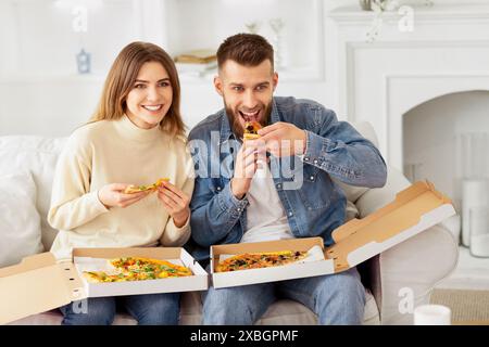 Mann und Frau essen Pizza auf der Couch Stockfoto