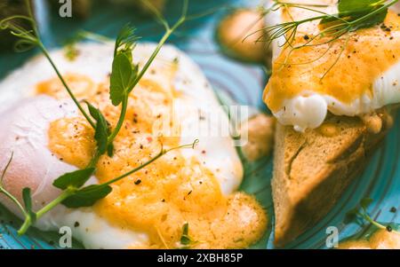 Pochiertes oder Benedikt-Ei mit Toast oder einer Scheibe Brot und Erbsengemüse auf einem türkisfarbenen Teller. Nahaufnahme. Ausgewählter Fokus. Hochwertige Fotos Stockfoto