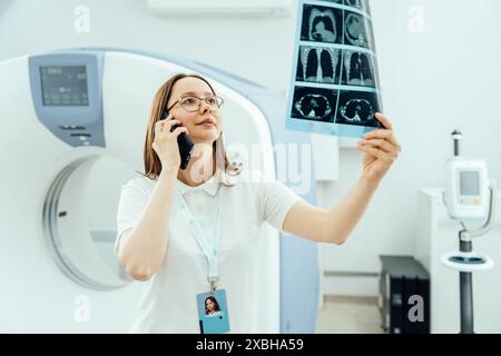 Eine Frau spricht auf ihrem Handy, während sie ein medizinisches Bild ansieht Stockfoto