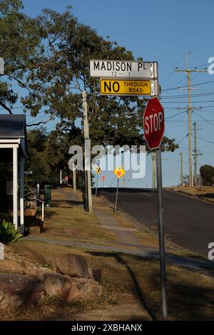 Stoppschild und Stromleitungen auf einer hügeligen Vorstadtstraße in Carina, Brisbane an einem hellen, sonnigen australischen Nachmittag Stockfoto