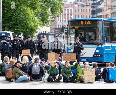 Am 11. Juni 2024 saßen Demonstranten auf der Straße und beobachteten Polizeibeamte im Kaisaniemi-Kreisverkehr in der Innenstadt von Helsinki. Stockfoto