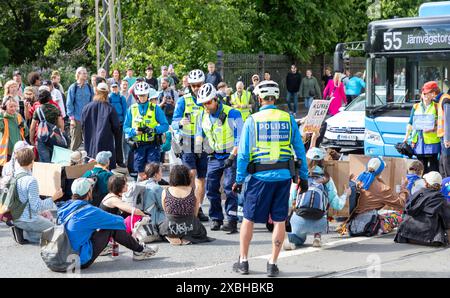 Polizeibeamte sprechen an Teilnehmer, die auf der Straße sitzen, um den Protest der „Sturmwarnung“ der Extinction Rebellion Finland in Kaisaniemi zu feiern. Stockfoto