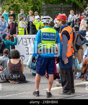 Protest-Verbindungsstelle und Unterhändler der Polizei, die beim „Sturmwarnung“-Protest der Extinction Rebellion Finland in Kaisaniemi diskutieren. Stockfoto