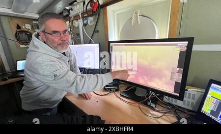 11. Juni 2024, Schleswig-Holstein, Kiel: Meeresgeologe Jens Greinert weist auf ein Unterwasserbild auf einem Monitor hin. Der Experte vom Geomar Helmholtz-Zentrum für Ozeanforschung in Kiel und sein Team untersuchen alte Munition in der Ostsee. (Zu dpa 'mit Käpt'n Blaubär' auf der Suche nach Munition in der Ostsee') Foto: Andre Klohn/dpa Stockfoto