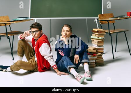 Junge Studenten, die sich lässig gekleidet haben, sitzen auf dem Boden, umgeben von Büchern. Stockfoto