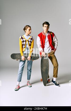 Zwei stilvolle junge Erwachsene halten Skateboards vor einem weißen Hintergrund. Stockfoto