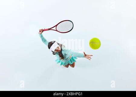 Luftaufnahme einer Tennisspielerin, eines Sportlers in der Mitte der Action, der Ball vor weißem Studiohintergrund serviert. Stockfoto