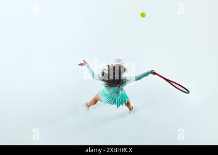 Draufsicht einer athletischen Frau in mintgrünem Tennisoutfit, die Serve vor weißem Studiohintergrund ausführt. Stockfoto